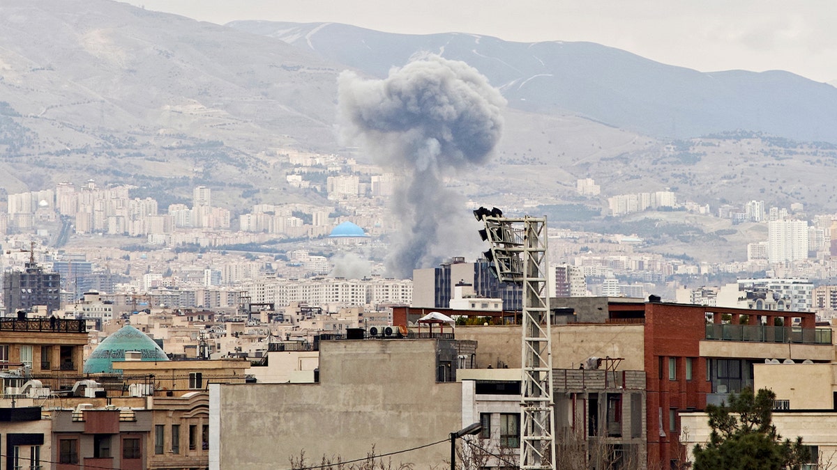 A tall column of smoke rising over Tehran after an explosion