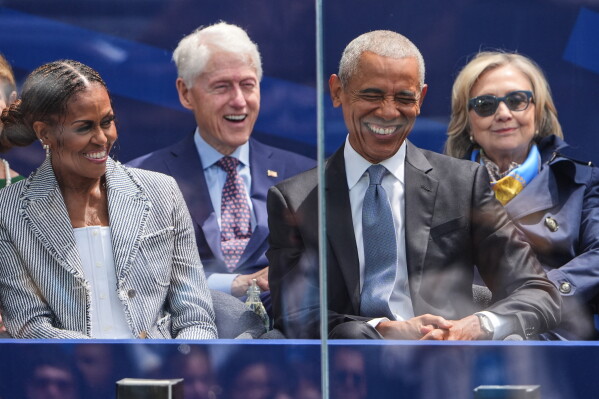 Former President Barack Obama, right, shares a laugh with former first lady Michelle Obama, left, on stage during the dedication ceremony for the Obama Presidential Center, Thursday, June 18, 2026, in Chicago. (AP Photo/Jeff Roberson)