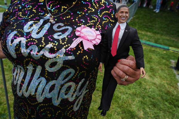 A woman holds a doll of former President Barak Obama as people watch the dedication ceremony for the Obama Presidential Center from Midway Plaisance, Thursday, June 18, 2026, in Chicago. (AP Photo/Nam Y. Huh)
