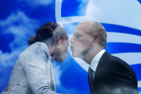 Former President Barack Obama, lean in to kiss former first lady Michelle Obama after speaking at the dedication ceremony for the Obama Presidential Center, Thursday, June 18, 2026, in Chicago. (AP Photo/Alex Brandon)