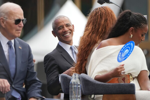Former President Barack Obama, center, smiles as he reacts to the musical performance by Stevie Wonder, also with Obama are from l-r., former President Joe Biden, and Obama's daughters Malia and Sasha during the dedication ceremony for the Obama Presidential Center, Thursday, June 18, 2026, in Chicago. (AP Photo/Alex Brandon)