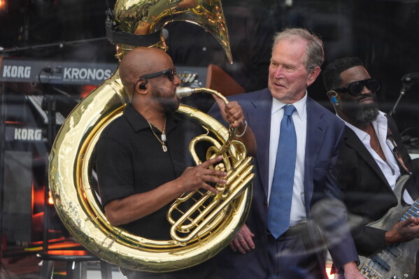 Former President George W. Bush, right, on stage with members of The Roots during the dedication ceremony for the Obama Presidential Center, Thursday, June 18, 2026, in Chicago. (AP Photo/Jeff Roberson)