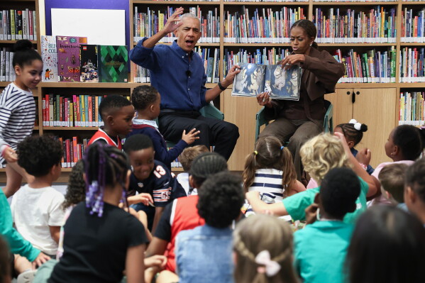 Former President Barack Obama, left, and former first lady Michelle Obama read to school children on opening day of the Barack Obama Presidential Center in John Lewis Plaza, Friday, June 19, 2026, in Chicago. (Win McNamee/Pool Photo via AP)
