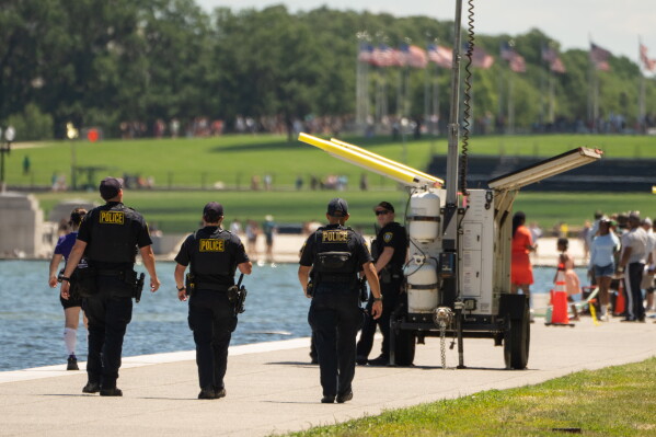 Oklahoma City Police Department officers, deputized to assist with local law enforcement for events around the 250th anniversary of the U.S., patrol near the area where sections of blue coating have peeled up in the Lincoln Memorial Reflecting Pool, Saturday, June 20, 2026, in Washington. (AP Photo/Mark Schiefelbein)