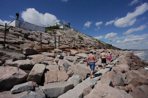 Beach-goers walk on a seawall below Taylor Swift house, Saturday, June 20, 2026, in Westerly, R.I. (AP Photo/Robert F. Bukaty)