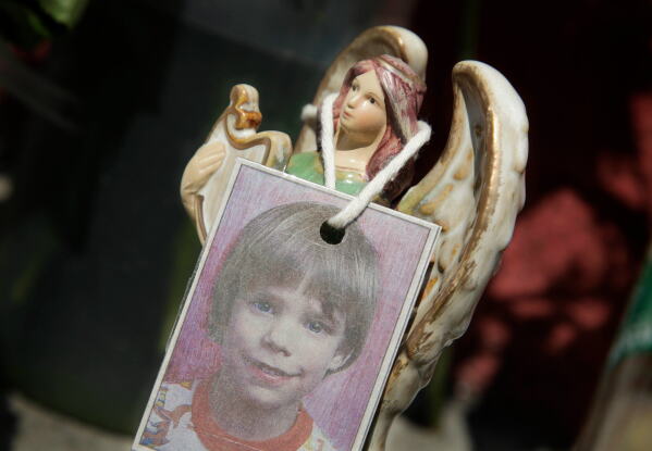 A photograph of Etan Patz hangs on an angel figurine, as part of a makeshift memorial in New York, May 28, 2012. (AP Photo/Mark Lennihan, File)