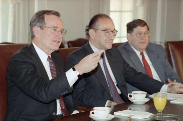 President George Bush gestures while meeting with economic advisors in the Cabinet Room of the White House, Jan. 15, 1991. Federal Reserve Board Chairman Alan Greenspan, center, and White House Chief of Staff John Sununu look on. (AP Photo/Doug Mills, file)