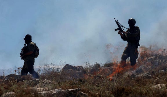 Israeli troops walk amid smoke rising from a fire started by crowd control grenades, during a protest against a settlement near Hebron in the West Bank, June 9, 2026.