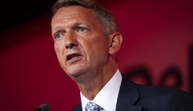 Andy Haldane speaking at a business conference, gesturing with hands, wearing a suit and tie, addressing economic issues.