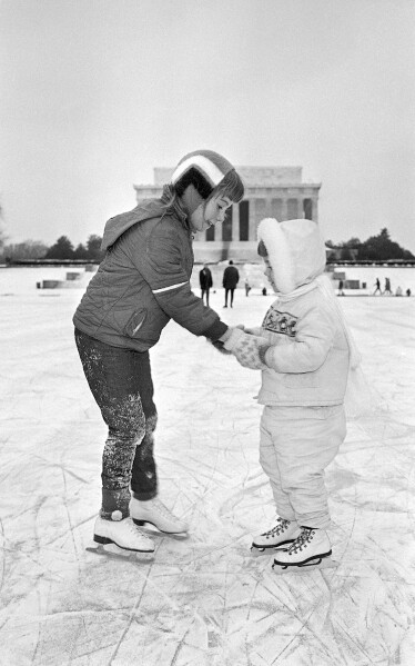 Washington residents Nanette Witter helps her younger sister, Dorinda, as they skate on Washington's frozen Reflecting Pool with the Lincoln Memorial in the background, on Jan. 10, 1968. (AP Photo/Charles Tasnadi)