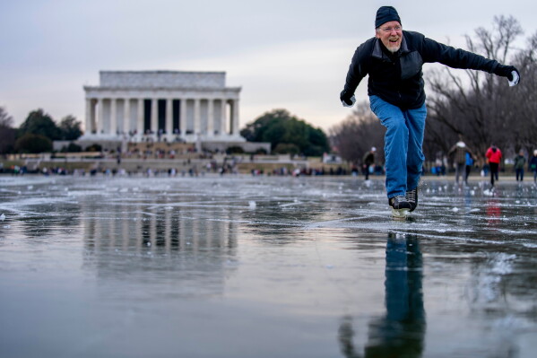 The Lincoln Memorial is visible as Dan DeMocker, of Tacoma Park, Md., slides pieces of ice toward his family as he ice skates on the frozen Reflecting Pool on the National Mall in Washington, Dec. 26, 2022. (AP Photo/Andrew Harnik, File)