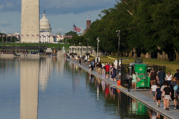 People walk along the Lincoln Memorial Reflecting Pool Tuesday, June 23, 2026, in Washington. (AP Photo/Jon Elswick)