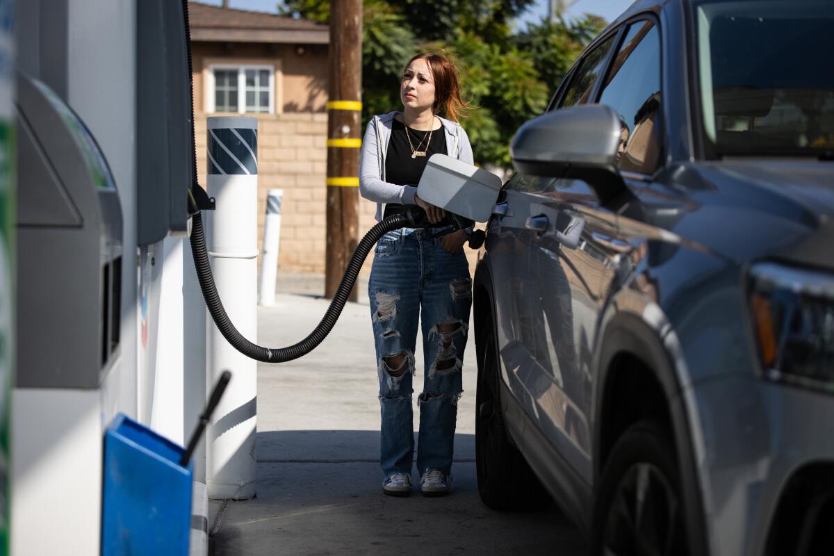 a woman pumps gas at a gas station
