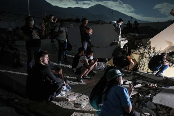 Residents watch rescuers' efforts to reach survivors beneath the rubble of a building that collapsed in the earthquakes in La Guaira, Venezuela, early Monday, June 29, 2026. (AP Photo/Matias Delacroix)