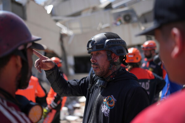 Volunteer Jean Sosa, who joined rescue teams searching for earthquake survivors, explains what he saw after going under the rubble of a building where rescuers are trying to reach trapped people in La Guaira, Venezuela, Monday, June 29, 2026. (AP Photo/Matias Delacroix)