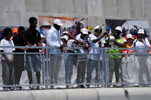 Faithful throw flowers into the sea as Pope Leo XIV attends a meeting with organisations working with migrants in Arguineguin at the Canary Islands, Spain, Thursday, June 11, 2026. (AP Photo/Alessandra Tarantino)