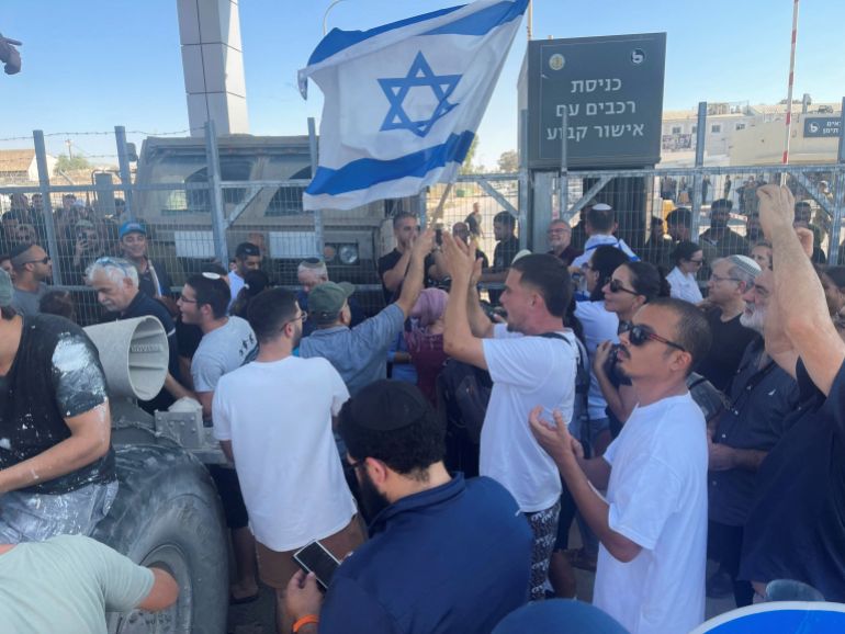 Right-wing protesters wave Israeli flags outside Sde Teiman detention facility, after Israeli Military Police arrived at the site as part of an investigation into suspected abuse of a Palestinian detainee, near Beersheba in southern Israel, July 29, 2024. [Jill Gralow/Reuters]
