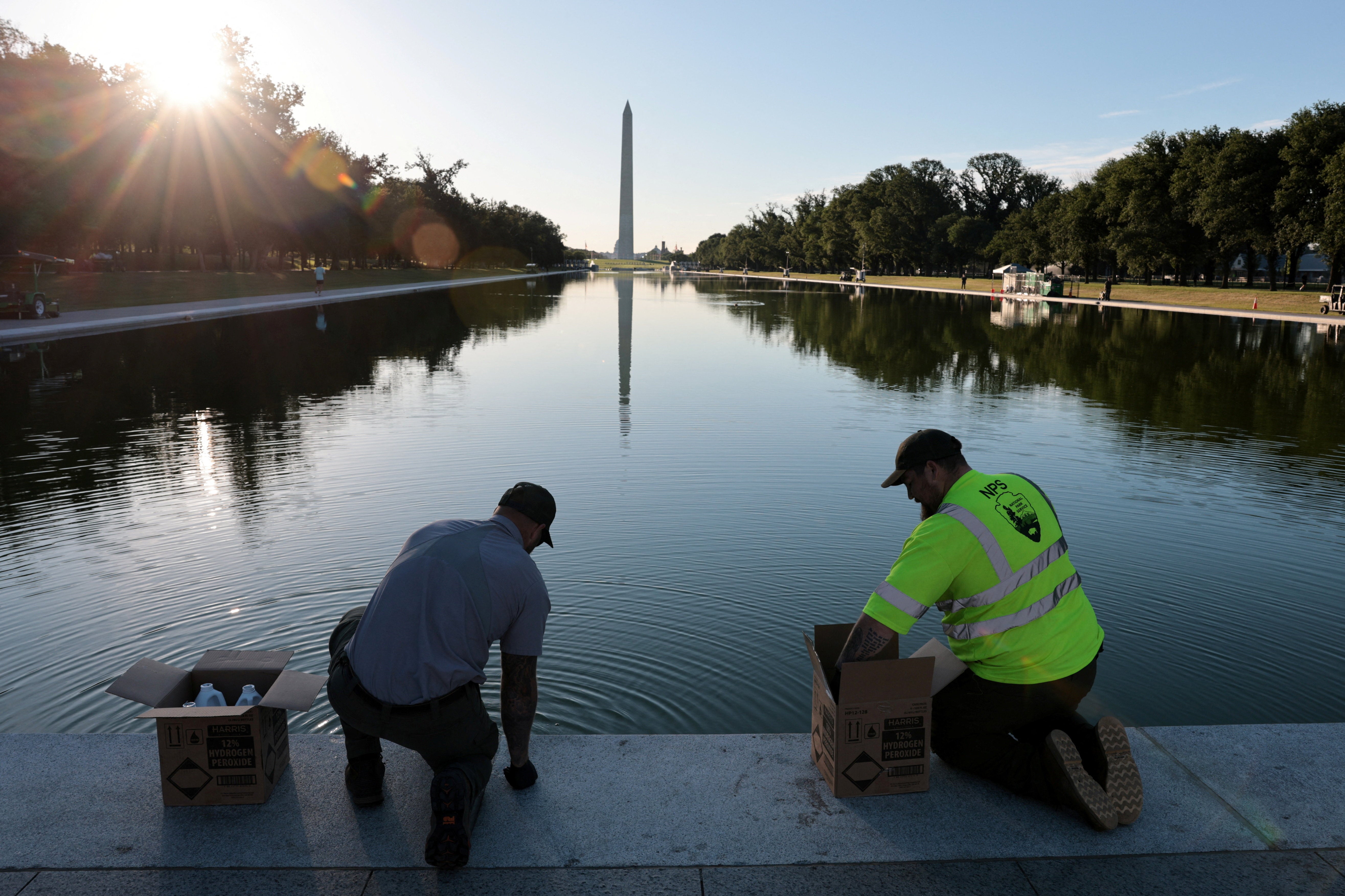 U.S. National Park Service workers dump bottles of hydrogen peroxide in the Lincoln Memorial Reflecting Pool as part of their effort to mitigate an algae bloom which followed the completion of recent renovations in Washington, D.C., U.S., June 16
