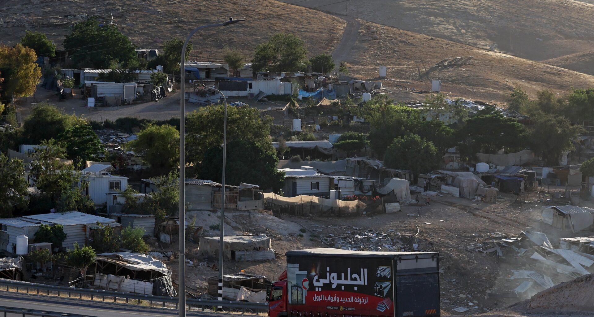 A truck drives past the Palestinian Bedouin village of Khan al-Ahmar occupied West Bank on May 20, 2026. Khan al-Ahmar sits near land Israel plans to use for its E1 development project that would facilitate settlement expansion in the area near Jerusalem; the village is facing an imminent threat of demolition and forced displacement.