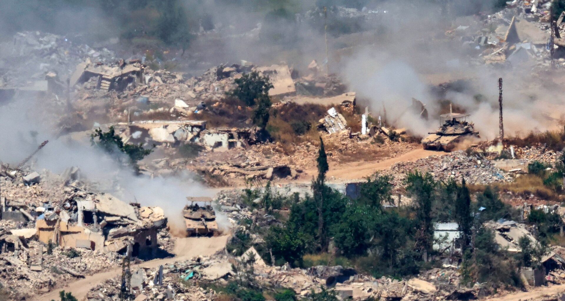 Israeli Merkava tanks drive along a road past destroyed buildings in southern Lebanon on June 17, 2026.