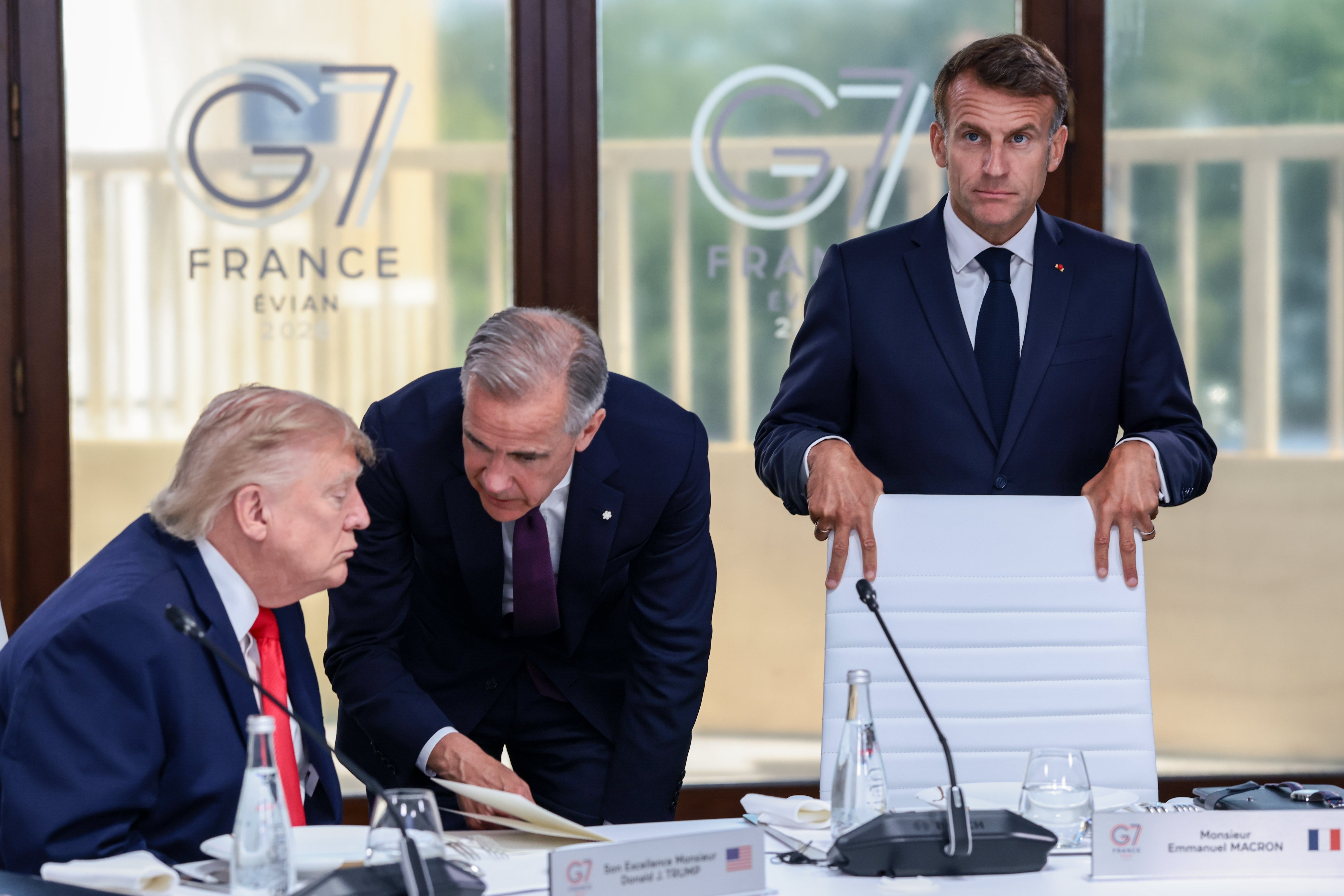 Donald Trump speaks with Canadian Prime Minister Mark Carney next to French President Emmanuel Macron