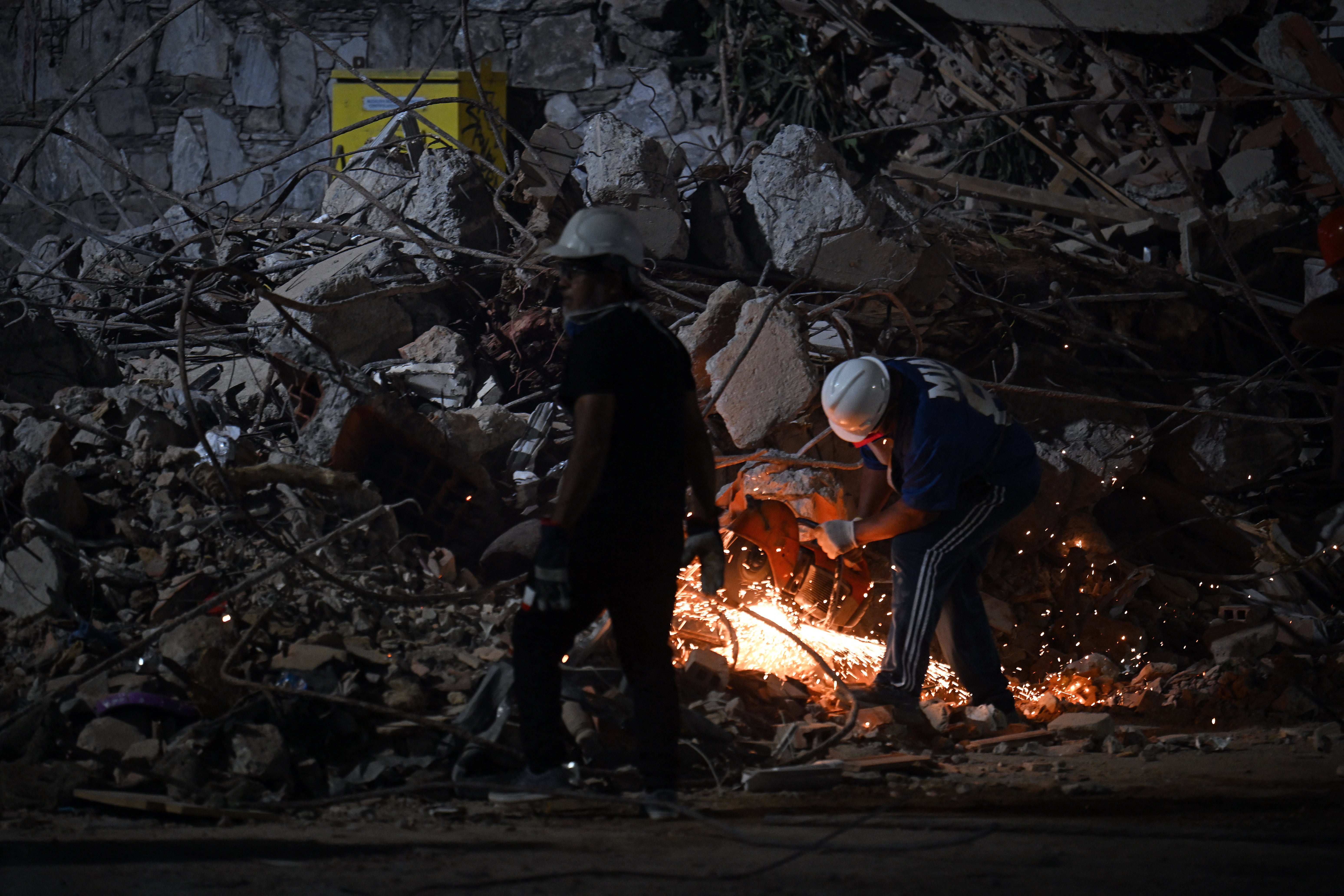 A rescuer cuts the steel bars of a collapsed building with an angle grinder in Caracas on June 25, 2026, following deadly earthquakes
