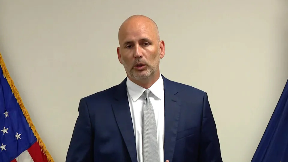image shows Mears speaking at a podium during press conference