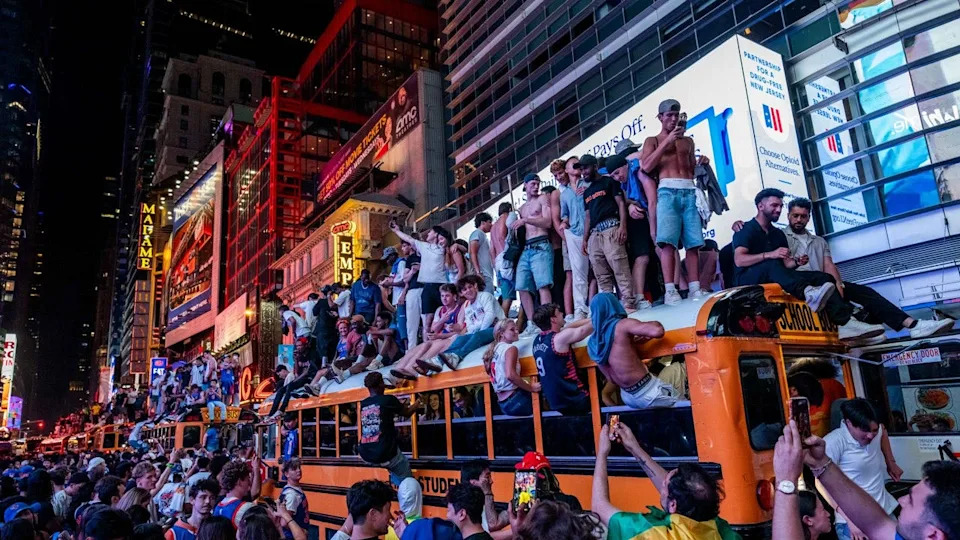 New York Knicks fans climb on buses as they celebrate after they win the NBA Finals in Times Square on June 14, 2026 in New York City.