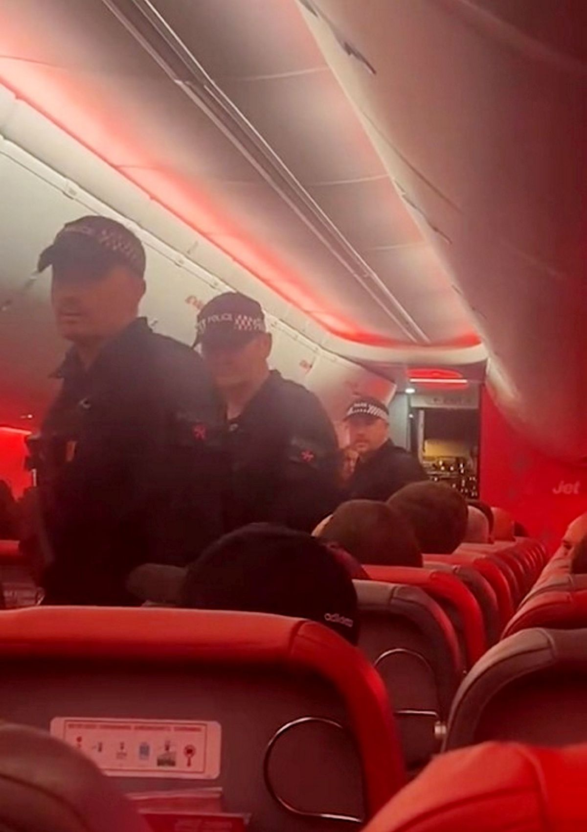 Police officers board the plane at Manchester airport. // A man was taken to hospital after being restrained on a Jet2 flight from Cyprus to Manchester. During the five-hour flight from Larnaca on June 21, 2026, a passenger allegedly became disruptive, pacing the aisle and shouting at other travellers. Witnesses claim he headbutted another passenger and threatened to fight others on board. According to two passengers who spoke to Talk to the Press, several travellers restrained the man until the aircraft landed at Manchester Airport, where police officers boarded and took over. The witnesses said officers began performing CPR on the passenger and later requested a defibrillator. The pilot reportedly informed passengers that the aircraft had become a crime scene, and travellers were subsequently taken by bus to a separate area of the airport to be questioned by police.