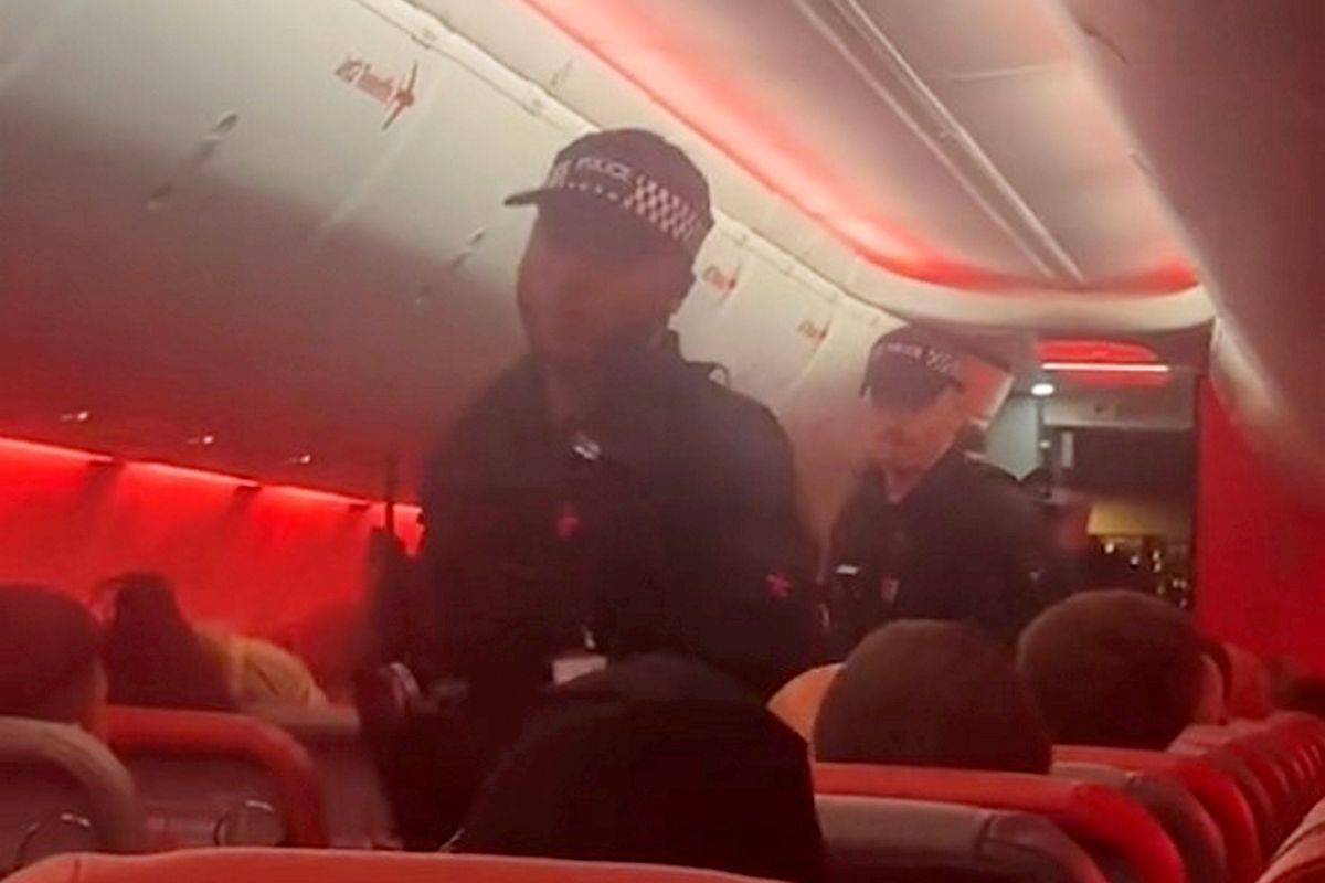 Police officers board the plane at Manchester airport. // A man was taken to hospital after being restrained on a Jet2 flight from Cyprus to Manchester. During the five-hour flight from Larnaca on June 21, 2026, a passenger allegedly became disruptive, pacing the aisle and shouting at other travellers. Witnesses claim he headbutted another passenger and threatened to fight others on board. According to two passengers who spoke to Talk to the Press, several travellers restrained the man until the aircraft landed at Manchester Airport, where police officers boarded and took over. The witnesses said officers began performing CPR on the passenger and later requested a defibrillator. The pilot reportedly informed passengers that the aircraft had become a crime scene, and travellers were subsequently taken by bus to a separate area of the airport to be questioned by police.