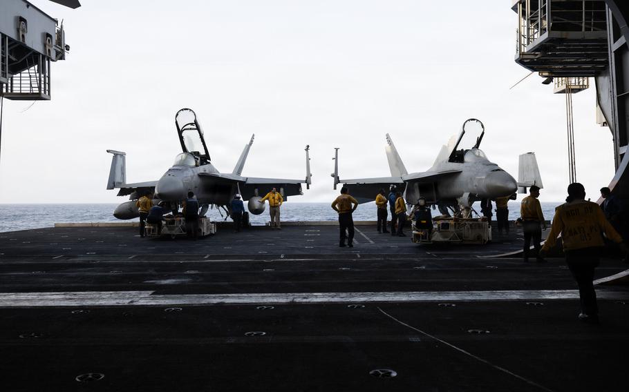 Sailors surrounding two aircraft carriers on a ship.