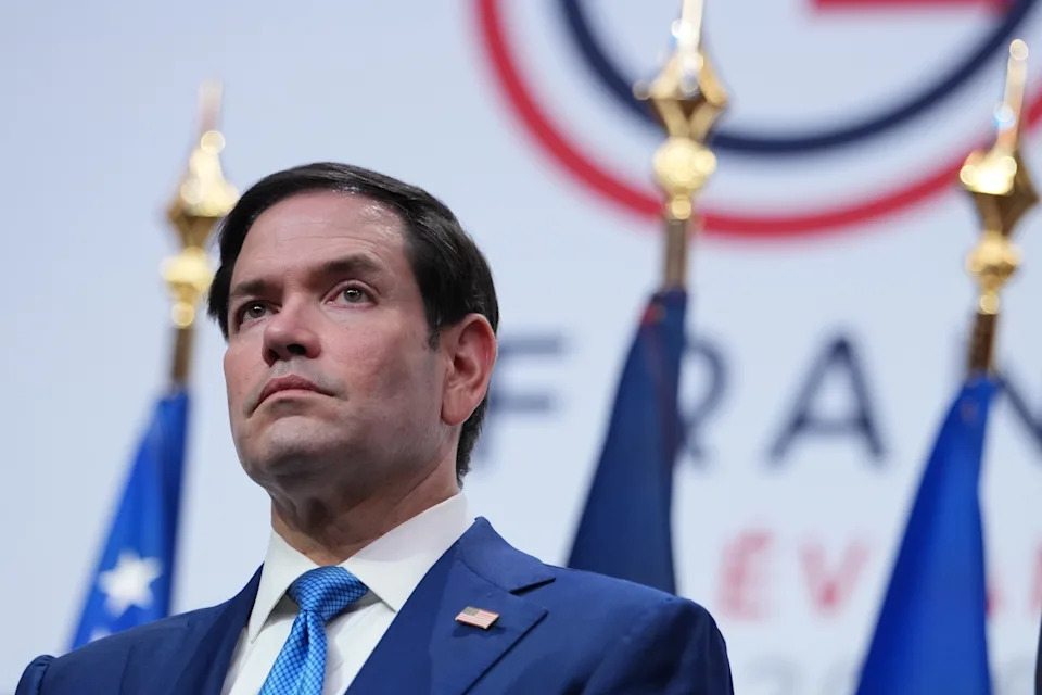 Julia Demaree Nikhinson/AP Photo/ - PHOTO: Secretary of State, Marco Rubio listens as President Donald Trump speaks during a news conference at the G7 summit, June 17, 2026, in Evian-les-Bains, France.