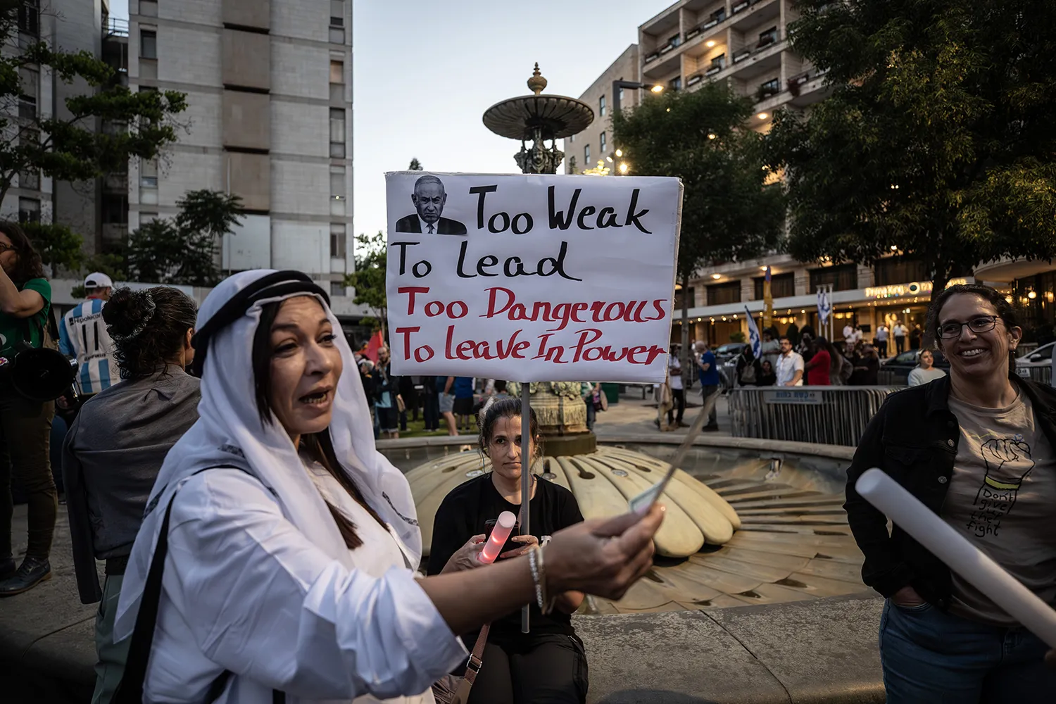 Protesters chanting slogans and carrying banners gather at Paris Square to demonstrate against Netanyahu in Jerusalem.