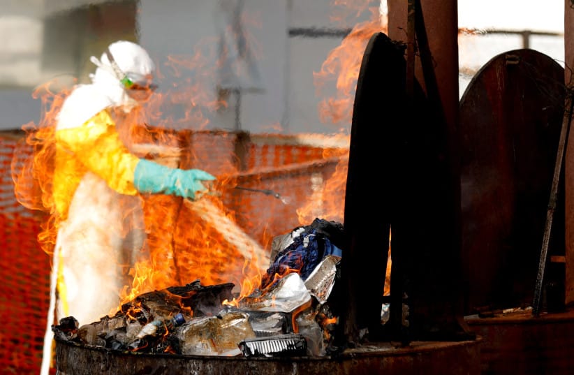 A health worker burns food waste of Ebola patients at an Ebola treatment center (ETC) in Katwa, near Butembo, in the Democratic Republic of Congo, October 5, 2019
