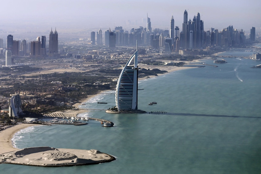 A birds-eye view of a hotel in the shape of a sail at the waters edge. 