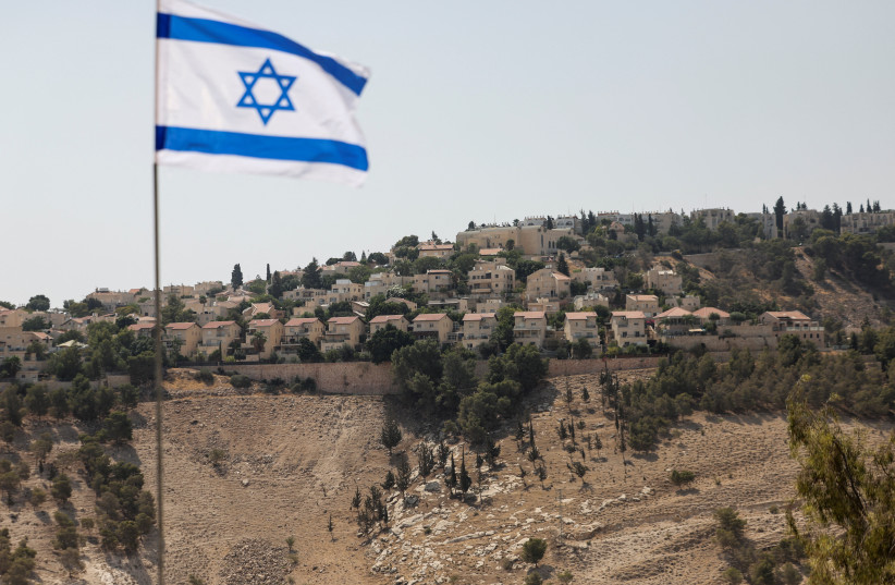 An Israeli flag flutters, as part of the Israeli settlement of Maale Adumim is visible in the background, in the West Bank, August 14, 2025.