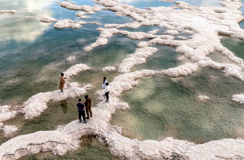 Visitors walk across salt formations along the receding shoreline of the Dead Sea, a stark sign of the region’s growing environmental crisis.