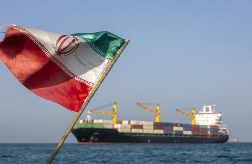 An Iranian flag flutters in the wind as ships remain anchored in the Strait of Hormuz on May 16. Negotiations between the US and Iran over opening this critical waterway have largely stalled. 