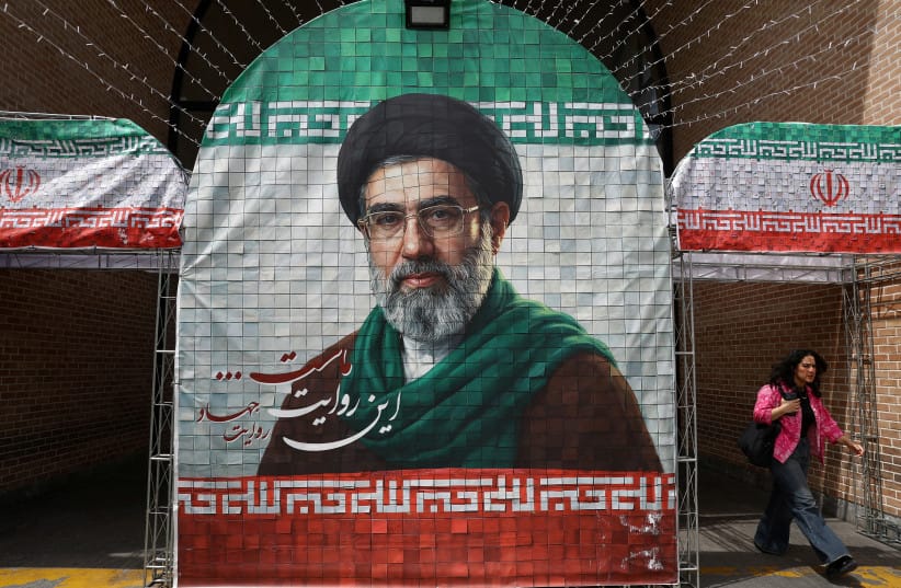 A woman walks next to a banner with a picture of Iran's new Supreme Leader Mojtaba Khamenei in Tehran, Iran, May 8, 2026.