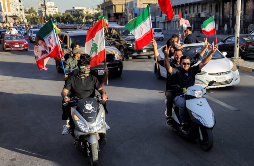 Youths ride vehicles while waving flags of Iraq, Iran, Lebanon and Hezbollah in Baghdad on June 15, 2026, during celebrations following the announcement of a deal to end the war between Iran and the US.