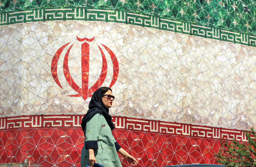 TOPSHOT-IRAN-US-ISRAEL-WAR TOPSHOT - An woman walks past a billboard displaying Iran's national flag at Enghelab Square in Tehran on June 14, 2026. US President Donald Trump said that a deal with Iran to end the Middle East war could be signed on June 14, and that the strategic Strait of Hormuz woul
