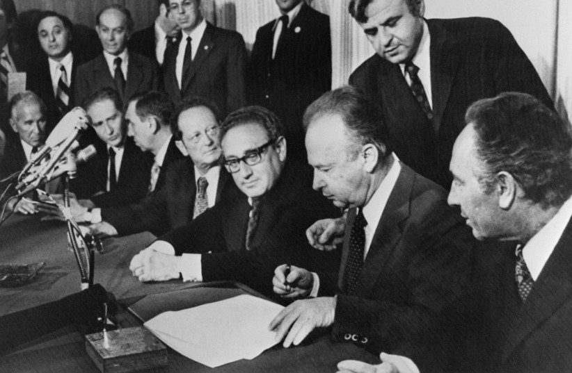 Israeli Prime Minister Yitzhak Rabin reads on September 2, 1975 in Jerusalem the Sinai Interim Agreement, also known as the Sinai II Agreement, diplomatic agreement signed by Egypt and Israel as Israeli Defence Minister Shimon Peres and US National Security Advisor Henry Kissinger look on.