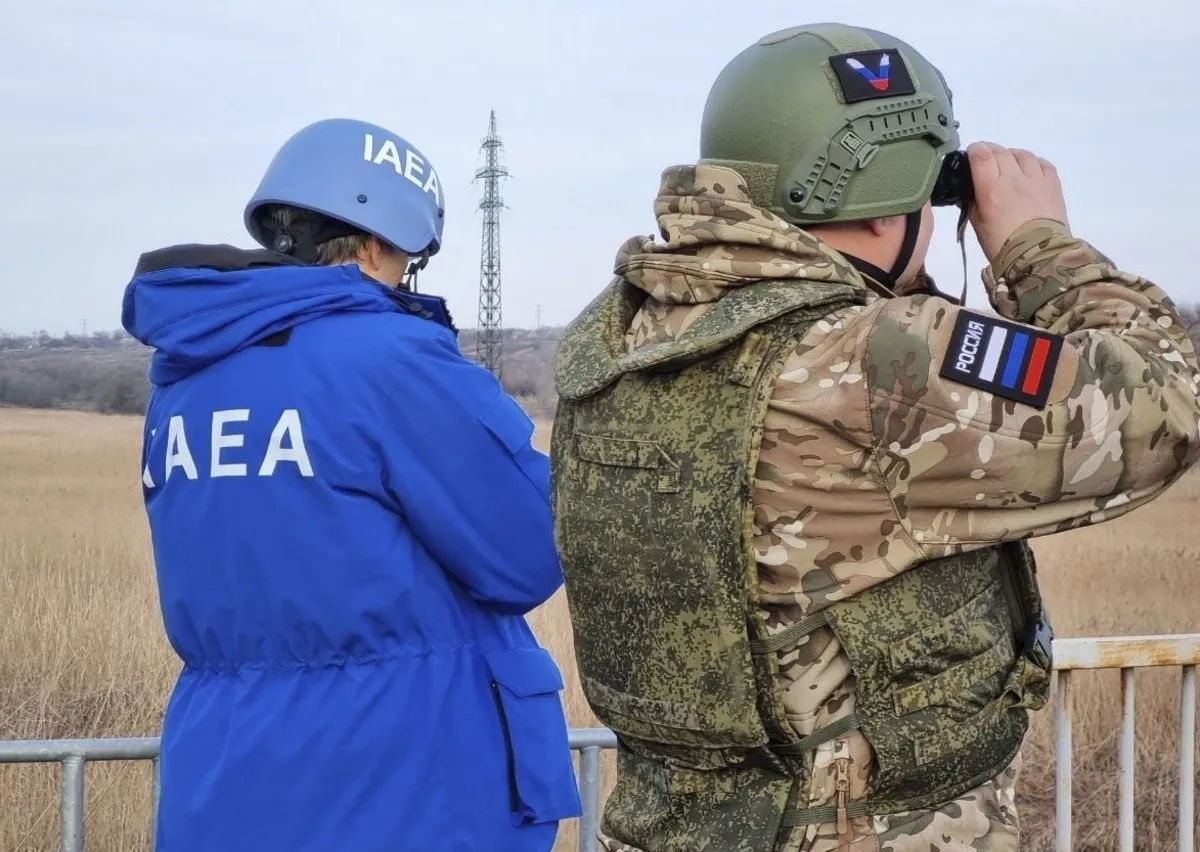 A Russian serviceman and a delegation members of the International Atomic Energy Agency (IAEA) cross the line of contact near the Karachekrak River on the territory of Zaporizhzhia region of Ukraine on February 7, 2024. This image was provided to AP by a third party and could not be independently verified.