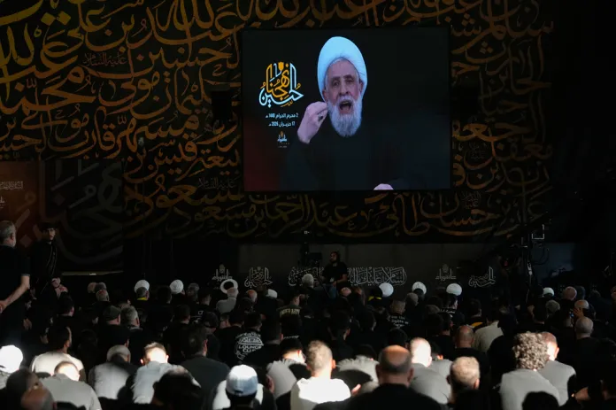 Hezbollah leader Sheikh Naim Qassem, is seen on a screen during a sermon marking the first day of Ashoura, the Shiite Muslim commemoration of the 7th-century death of Imam Hussein, the grandson of the Prophet Muhammad, at the grave of late Hezbollah leader Sayyed Hassan Nasrallah, left, in Beirut, Lebanon, Wednesday, June 17, 2026.