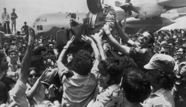 A cheering crowd at Ben-Gurion Airport raises a soldier in the rescue squad that freed the hijacked hostages from Uganda earlier in the day, July 4, 1976.  In the background is the C-130 transport plane which took part in the raid. The rescuer's face is obscured for security reasons. (AP Photo/Pool)
