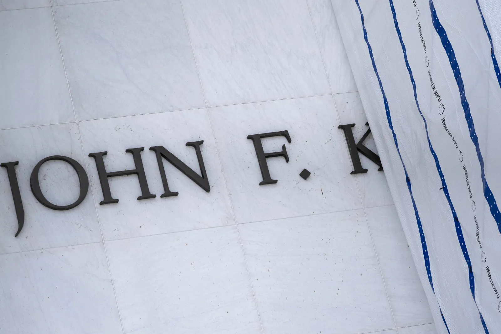 Some of the lettering is seen as a tarp covers signage on the facade of the Kennedy Center in Washington, DC, on June 15, 2026.
