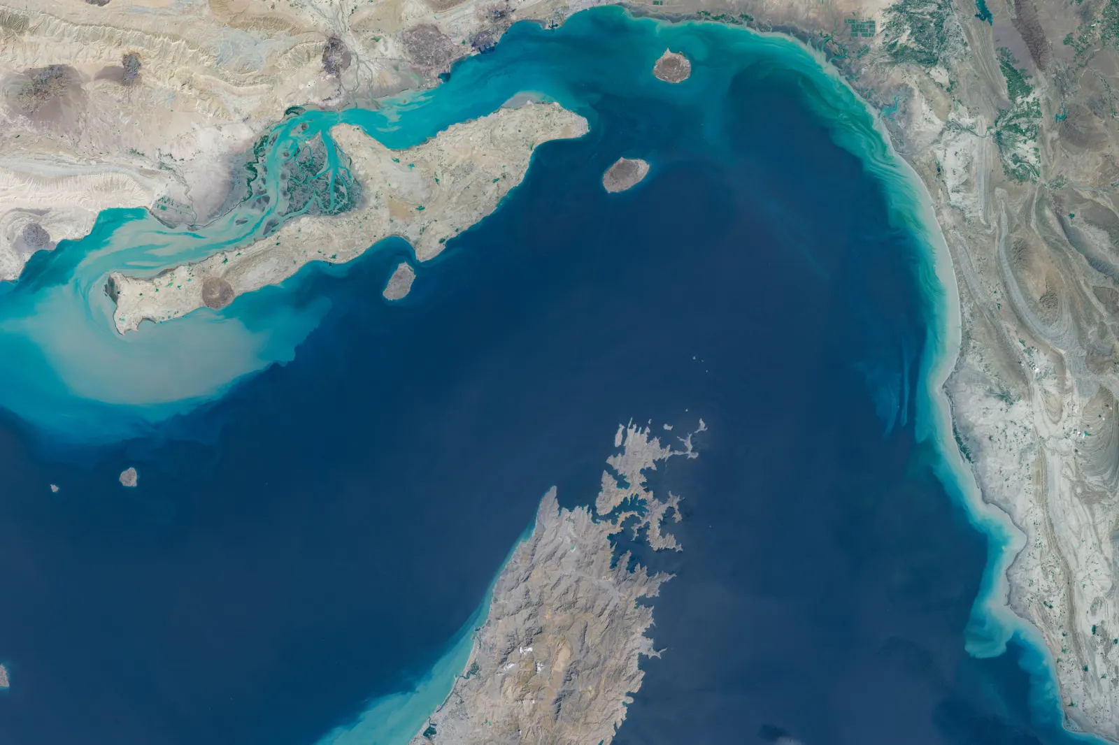 Satellite imagery dated April 7, 2026, shows a broad view of the Strait of Hormuz between southern Iran and Oman's Musandam Peninsula, including surrounding islands, coastal terrain, and turquoise shallow-water zones at the entrance to the Persian Gulf.