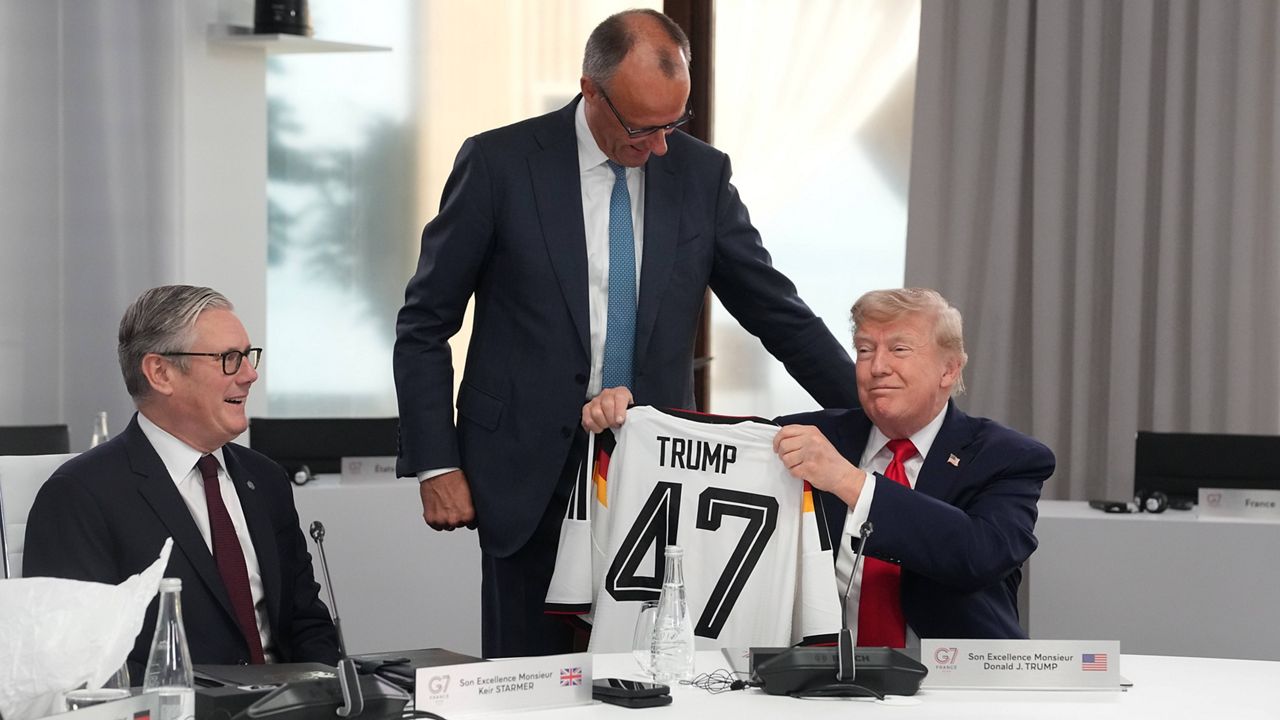 U.S. President Donald Trump, right, holds up a jersey with the number 47 on it as British Prime Minister Keir Starmer, left, and German Chancellor Friedrich Merz look on during a working session at the G7 summit in Evian-les-Bains, France, Tuesday, June 16, 2026. (AP Photo/Thibault Camus, Pool)
