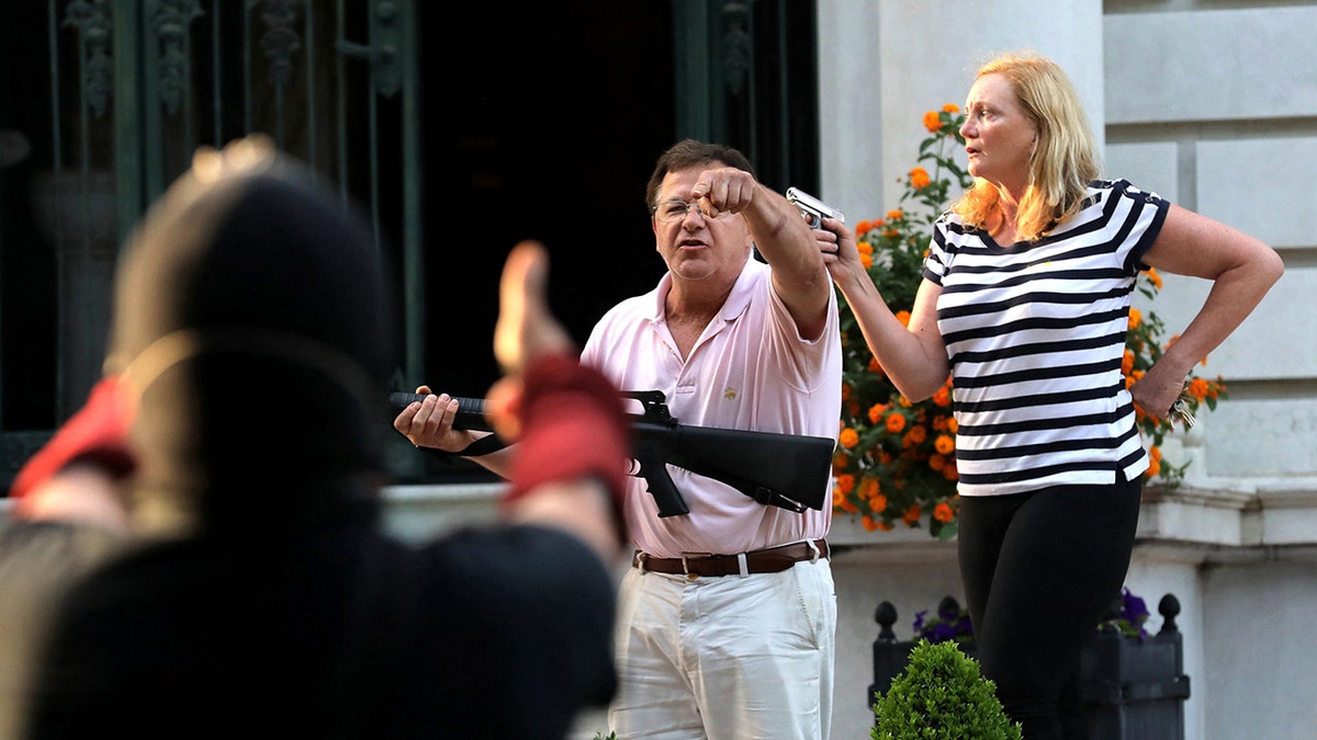 Armed homeowners Mark T. and Patricia N. McCloskey standing in front of their house holding guns