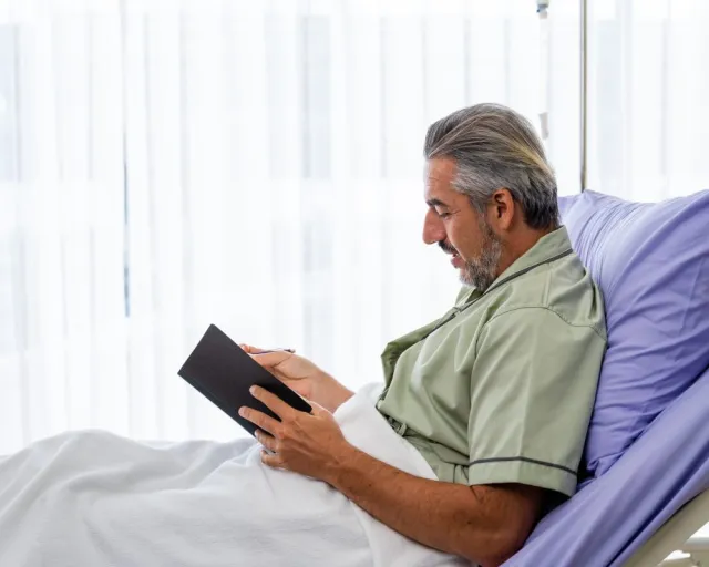 Caucasian mid adult patient writing a diary while recovering in the hospital ward - stock photo